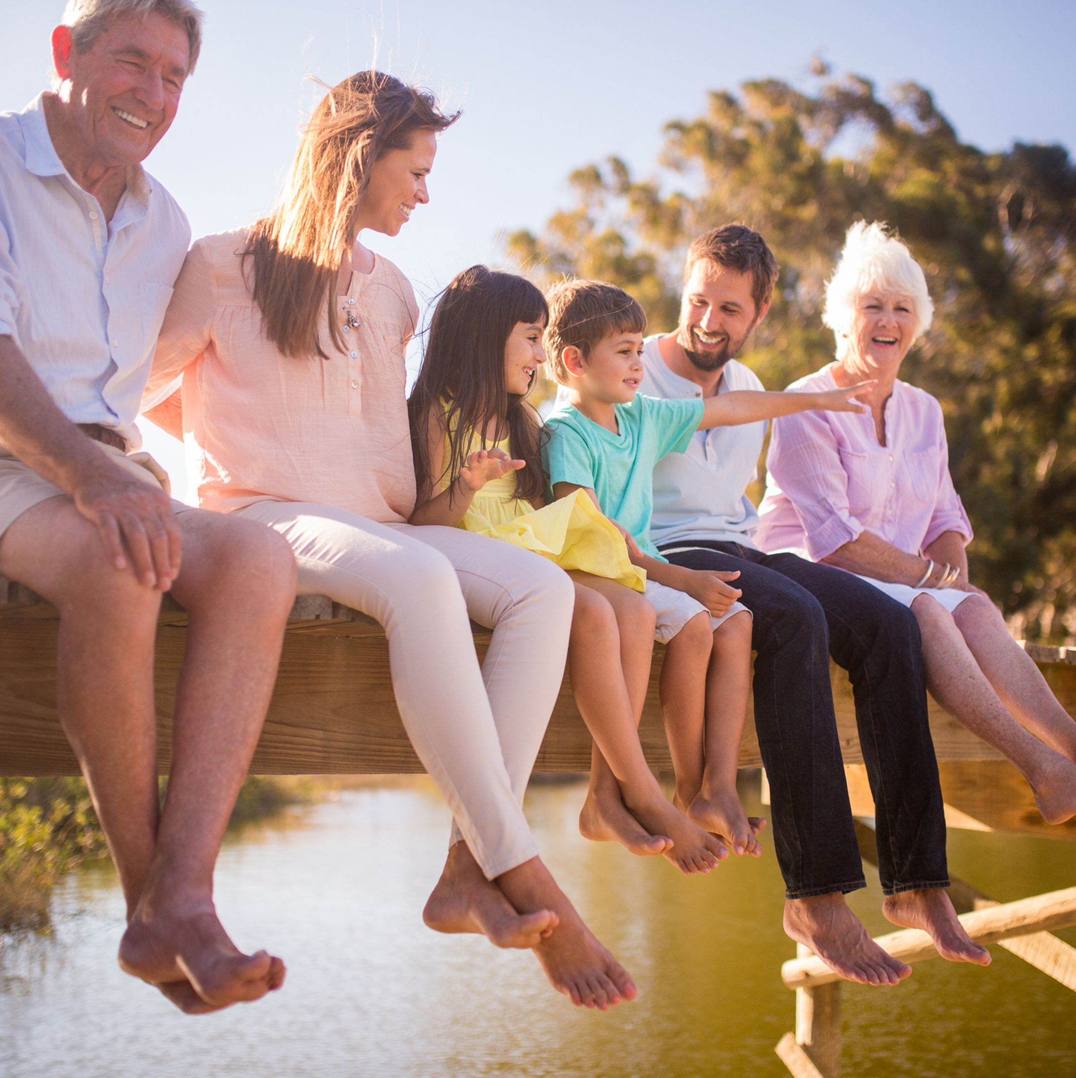 Generations of a family sitting in a row outside on a dock