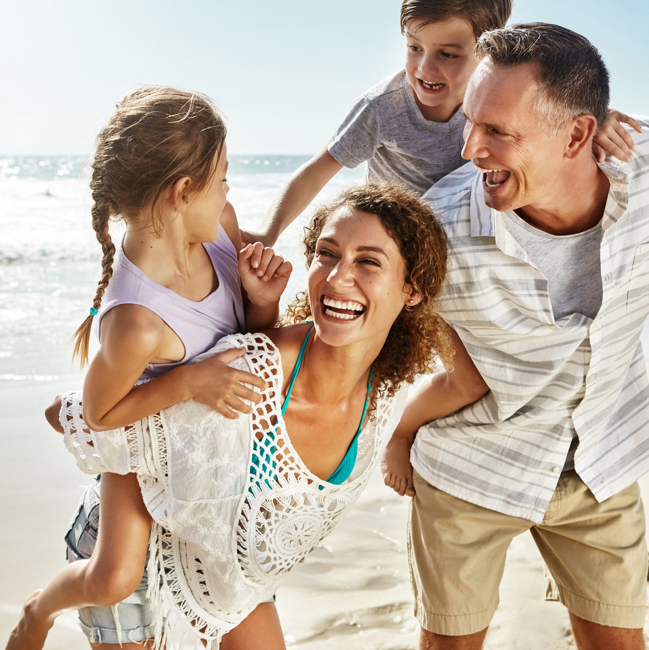 Family of four smiling and enjoying their time on the beach