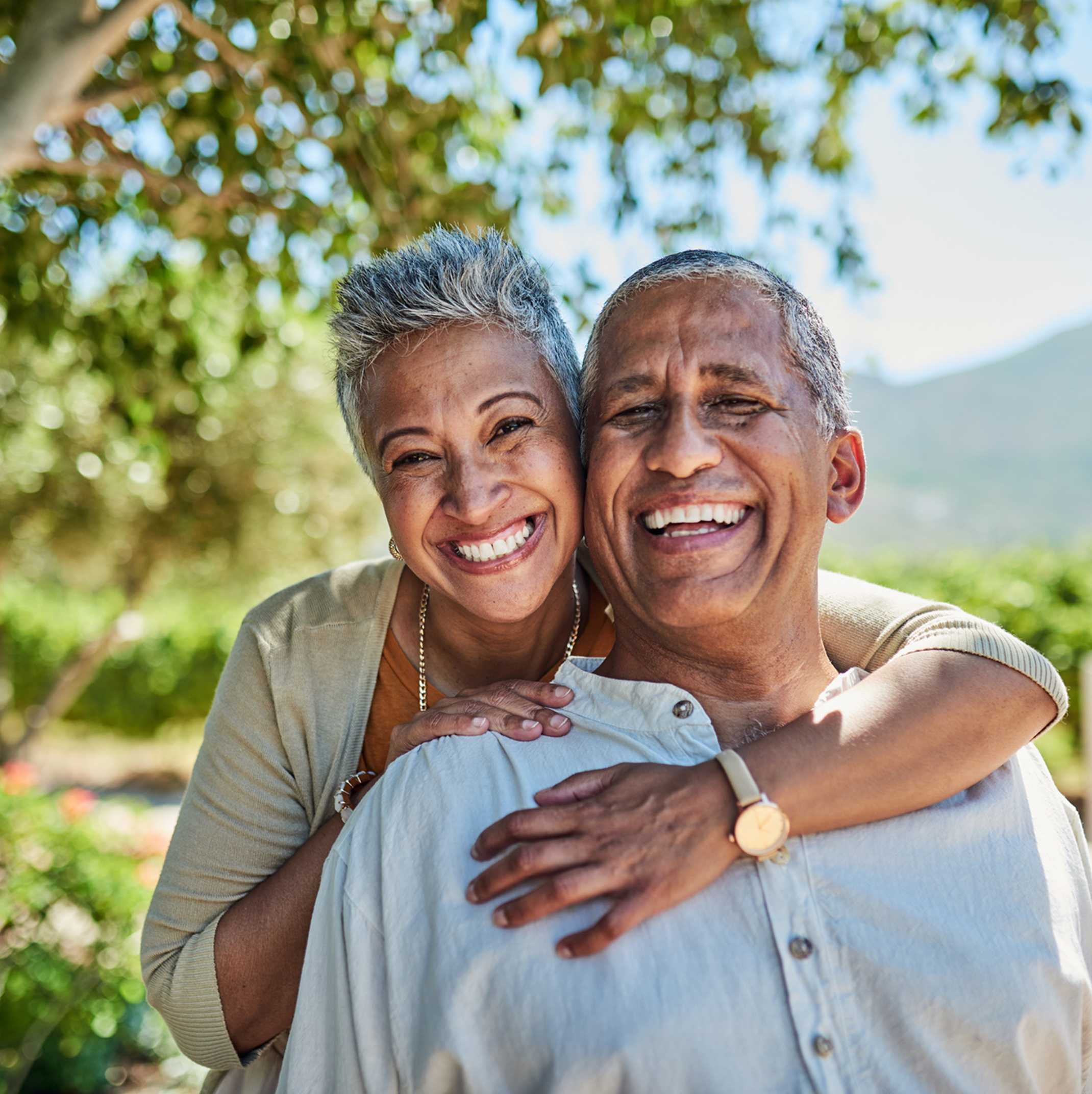 Couple outside in each other’s warm embrace smiling at the camera