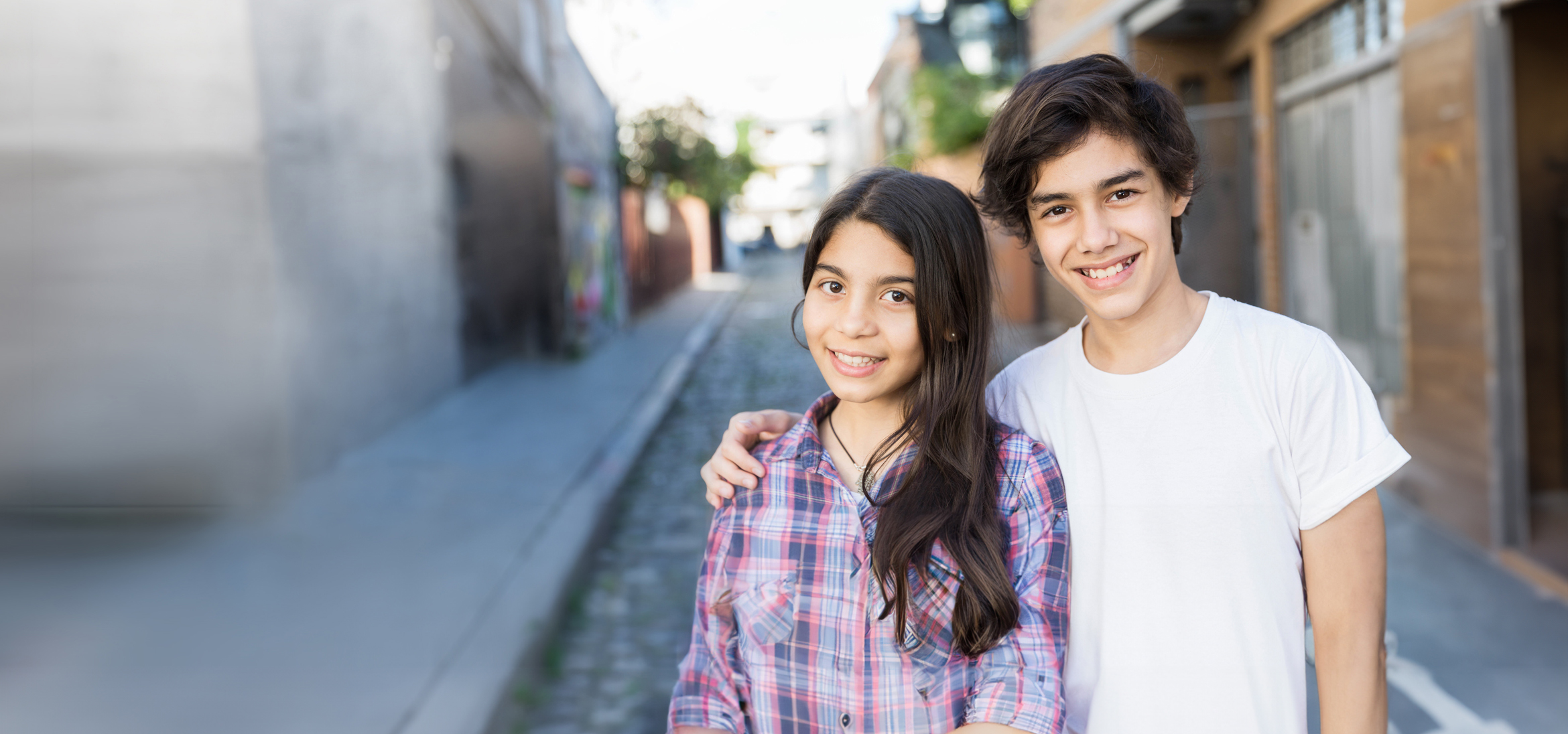 Teenage brother and sister smiling together outside